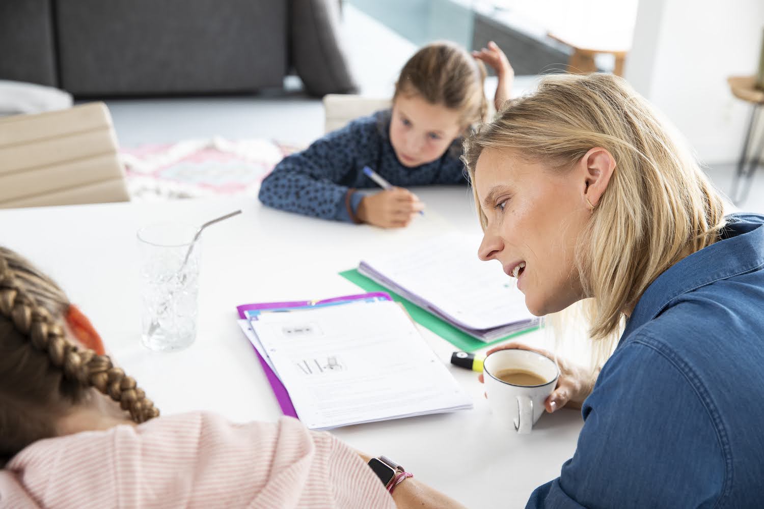 mama aan tafel met kinderen die huiswerk maken