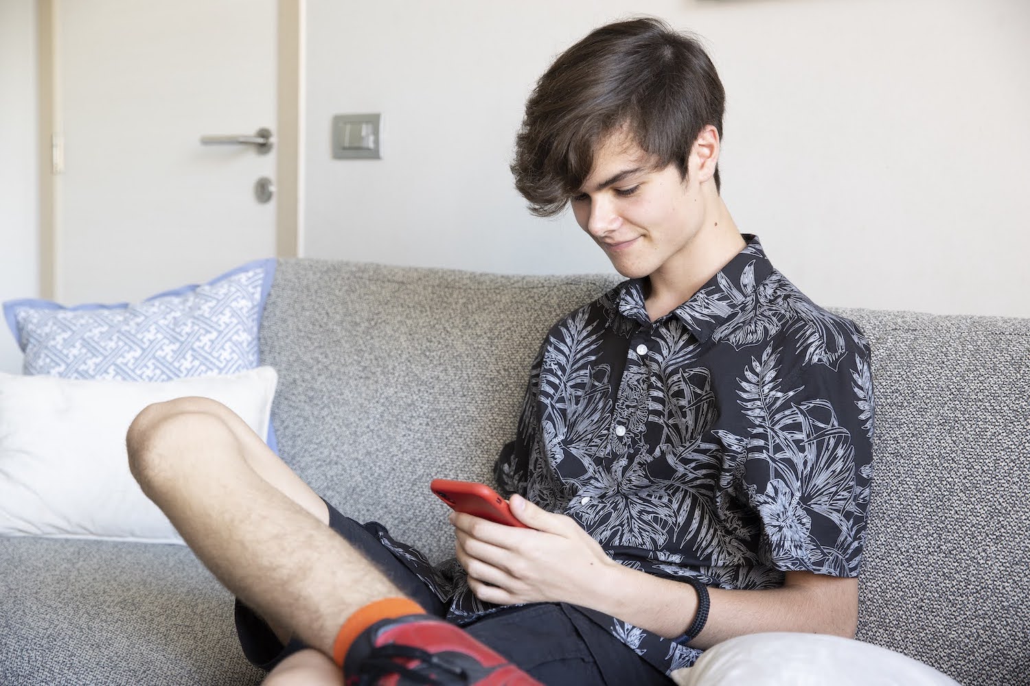 Tienerjongen met smartphone op de zetel
