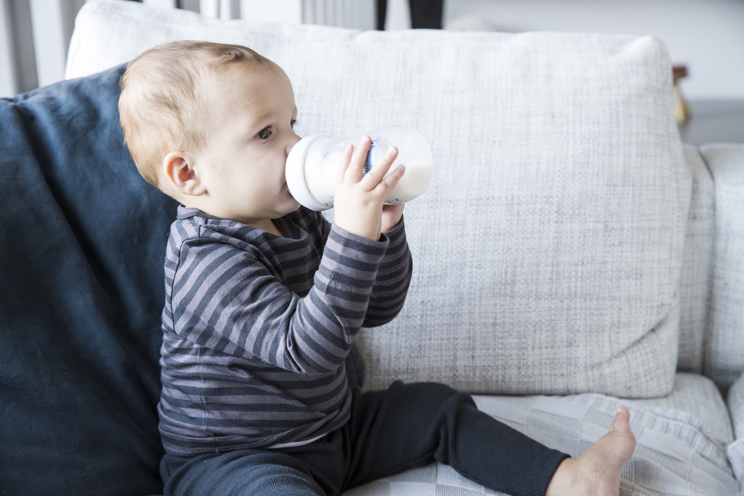 peuter drinkt flesje melk in de zetel