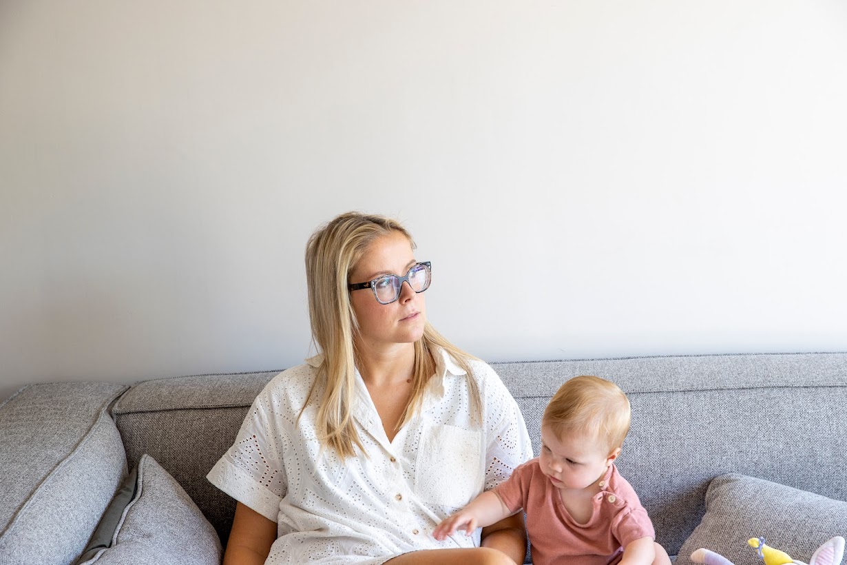 vrouw staart naar buiten met baby op schoot