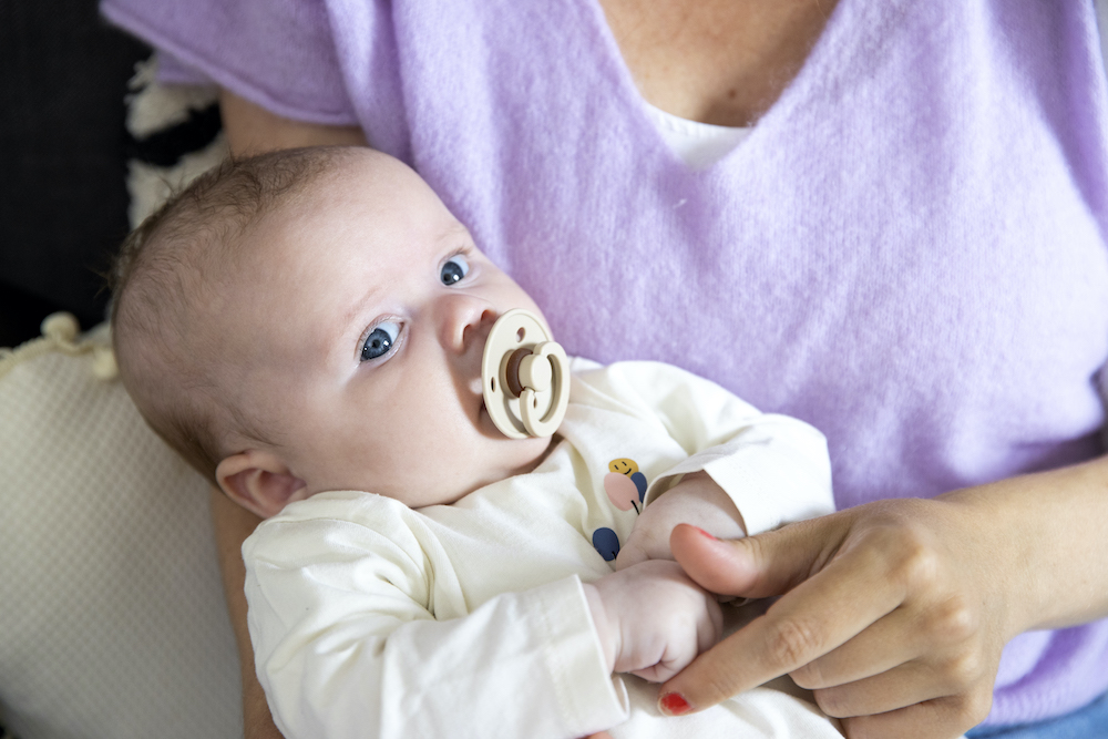 baby met tutje in de mond op arm van mama