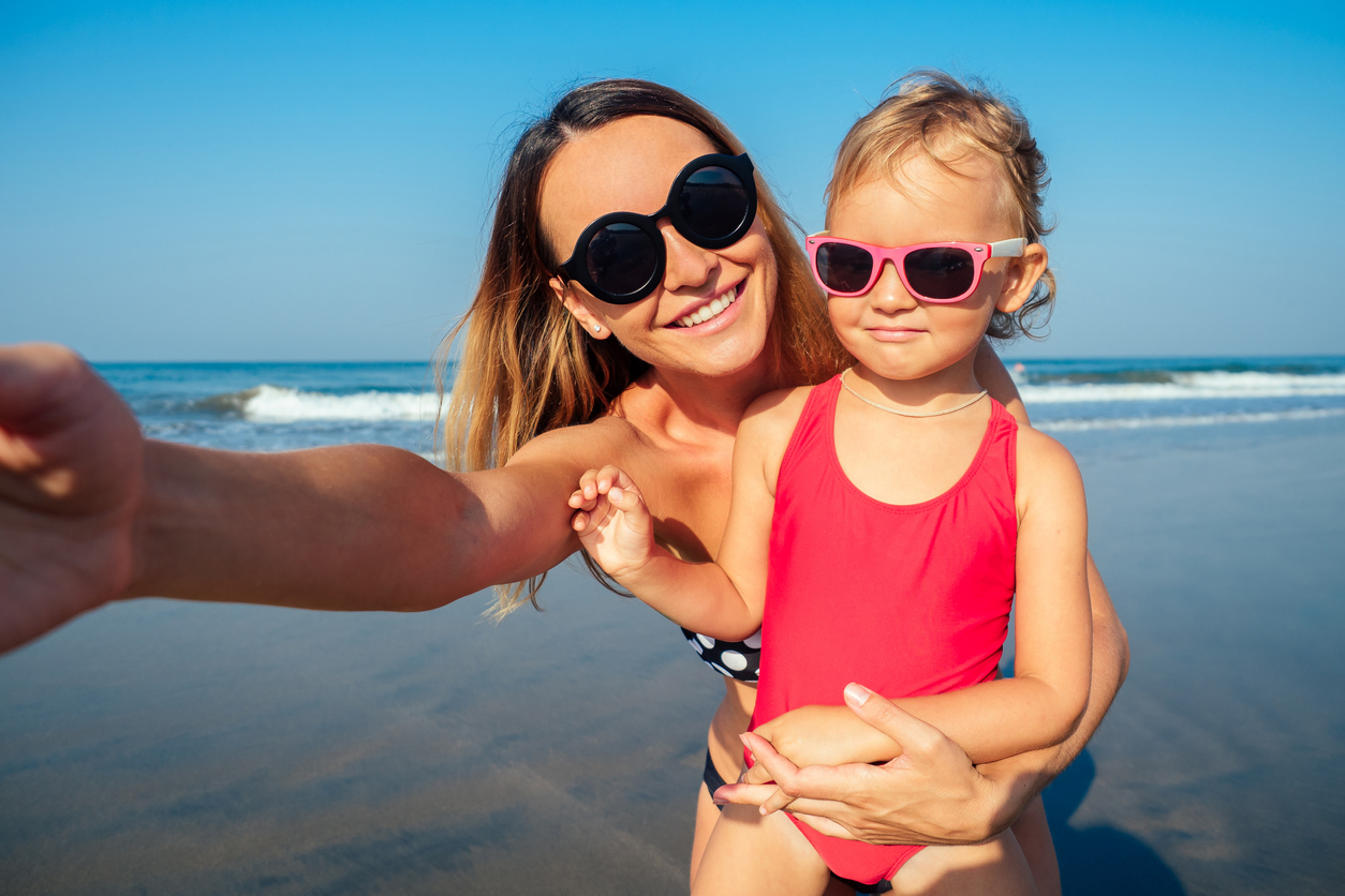 mama neemt selfie op strand met peuter