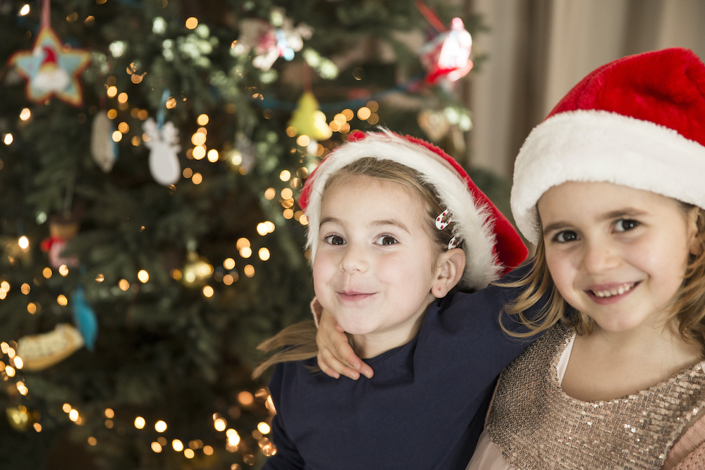 meisjes met kerstmuts naast kerstboom