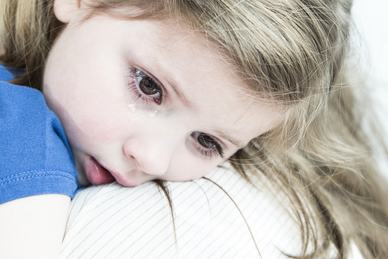 Verdrietig meisje ligt bij mama op de arm