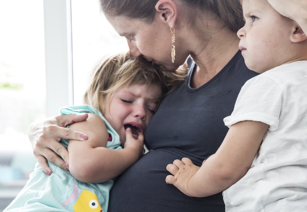 Mama is zwanger en troost wenende dochter