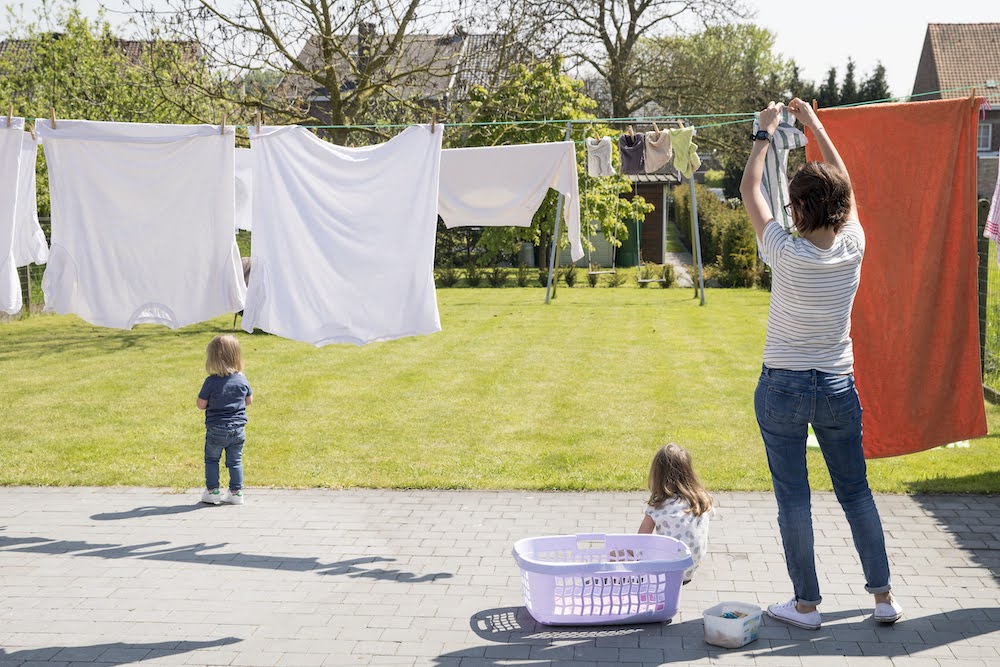 mama hangt was op met kindjes in de tuin