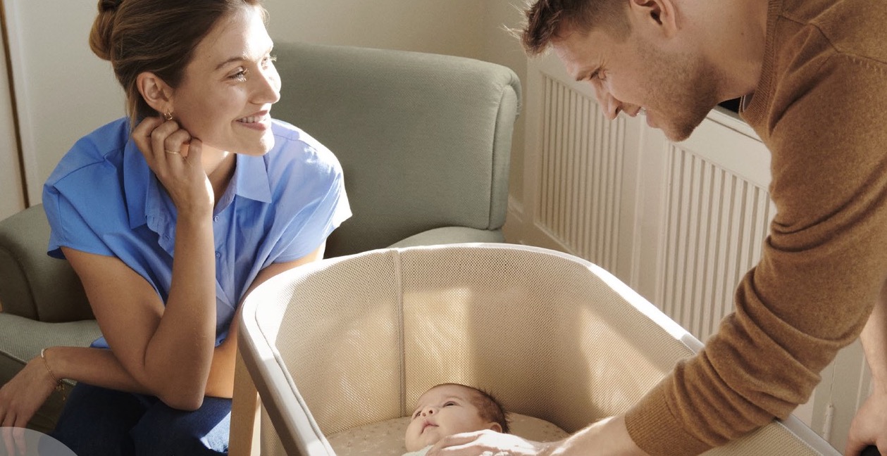 Mama en papa naast babi in reisbedje Snoozi van Stokke