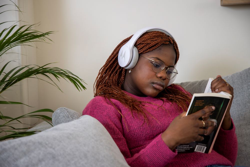 tiener leest boek met koptelefoon