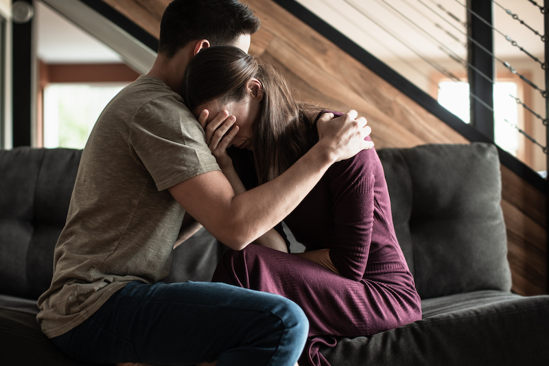 Man omarmt vrouw met verdriet