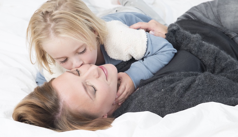 mama en dochter knuffelen in bed