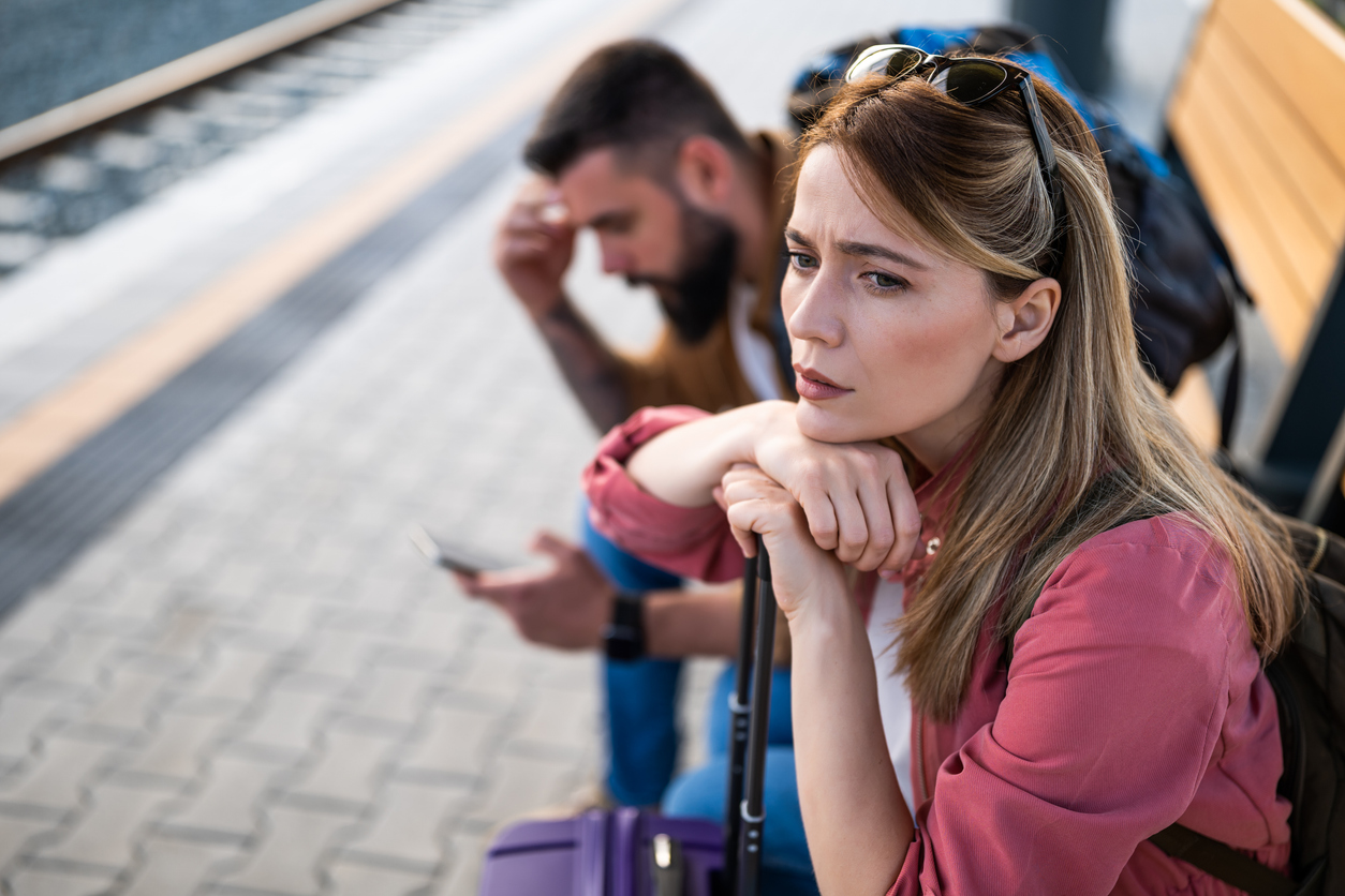 vrouw en man zitten op bank in station