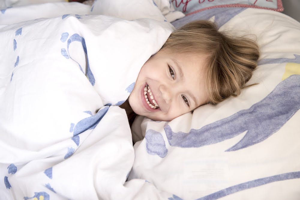 Kleuter ligt lachend in bed