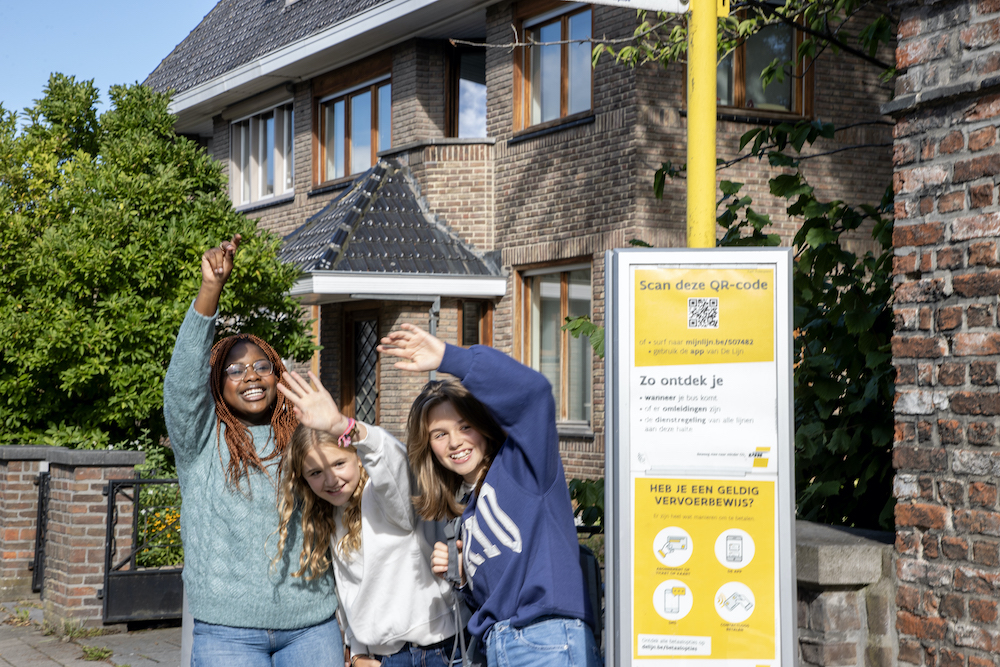 tienermeisjes wachten op de bus en doen teken om te stoppen