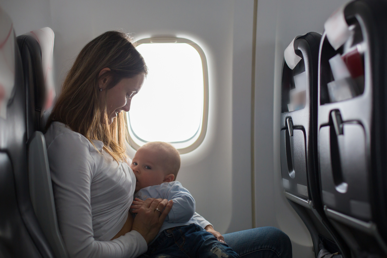 mama geeft baby borstvoeding in vliegtuig