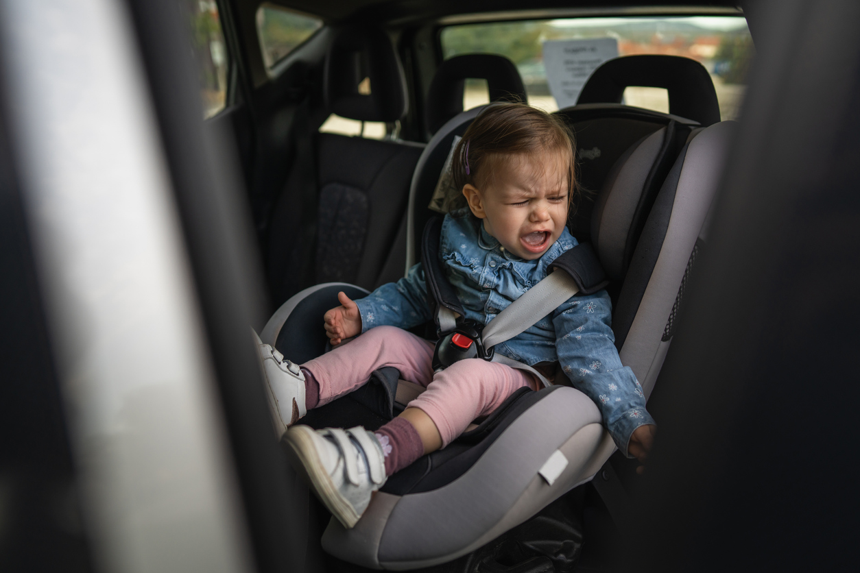 Wenende peuter op de achterbank van de auto