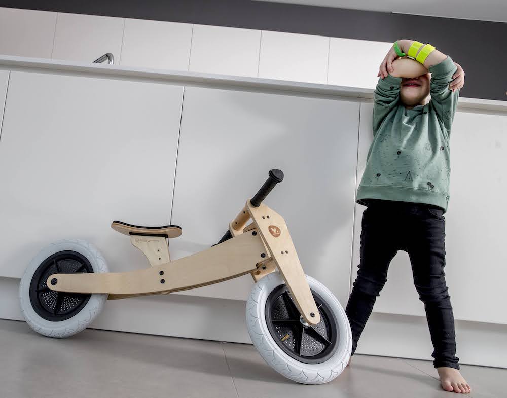jongen staat naast loopfiets en weent