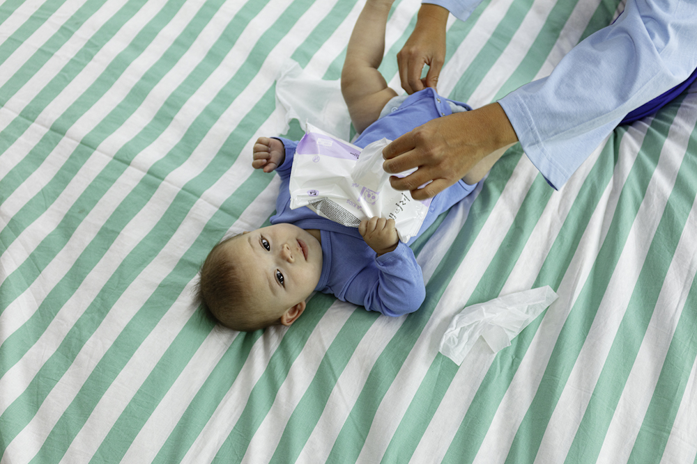 Baby ligt neer en houdt vochtige doekjes vast