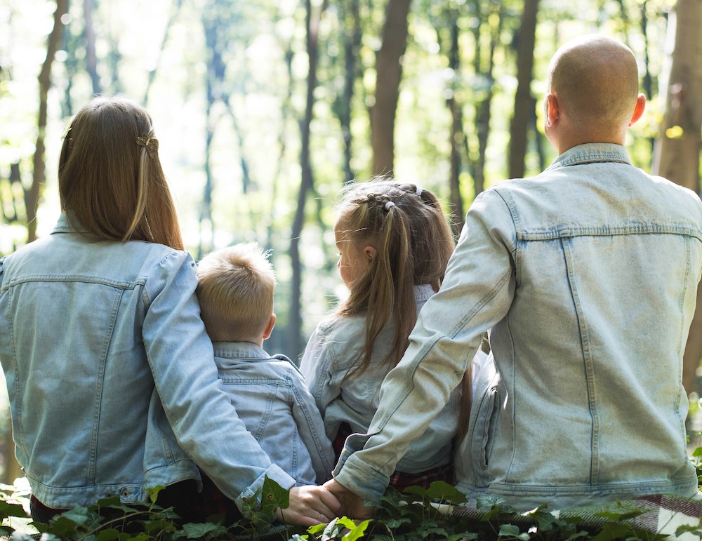mama en papa met zoon en dochter zitten in het bos