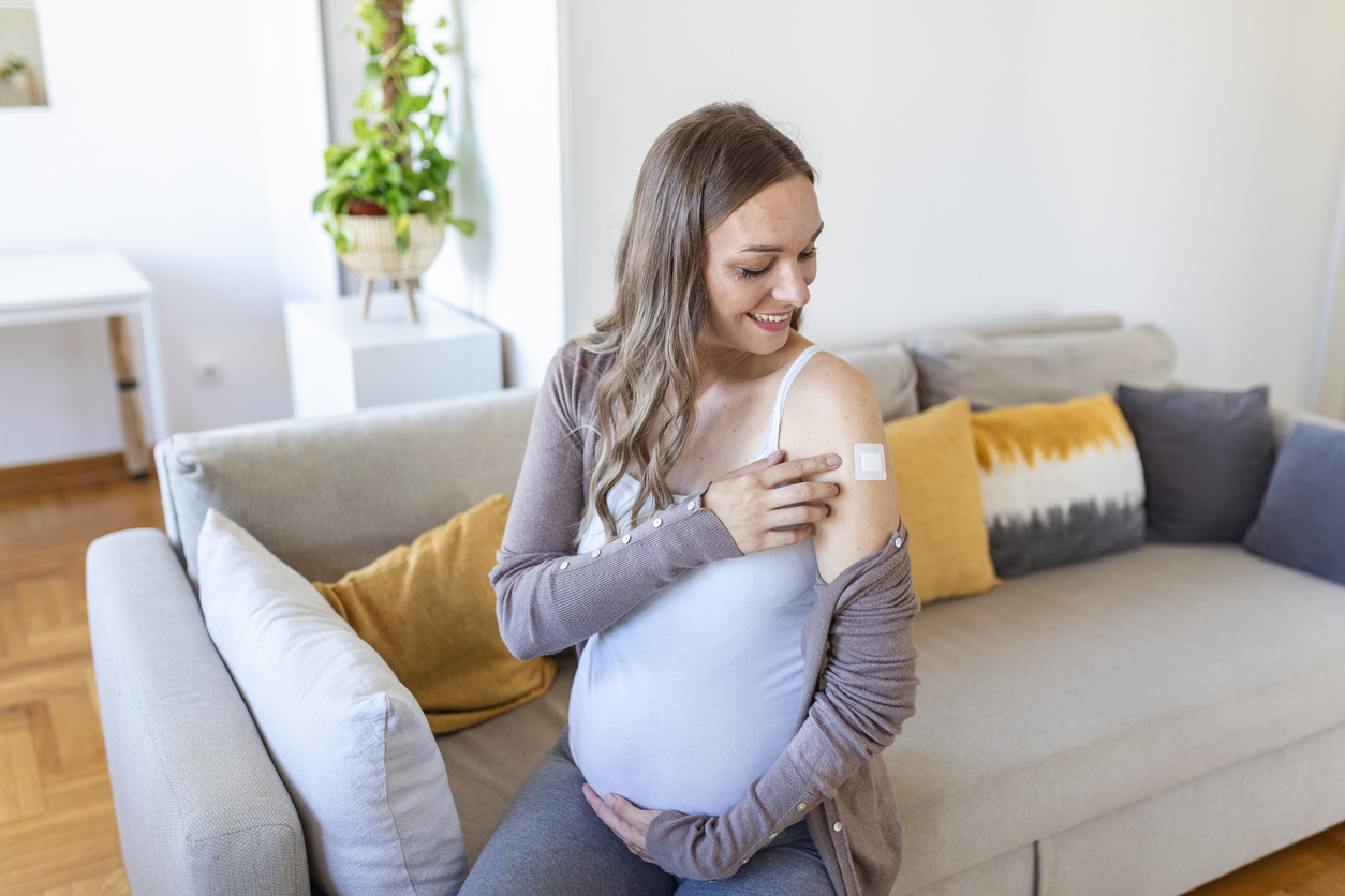 Zwangere vrouw met pleister op arm na vaccin