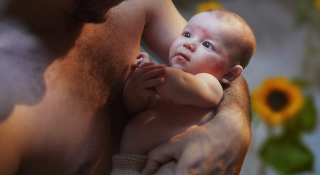Baby ligt in de armen van papa