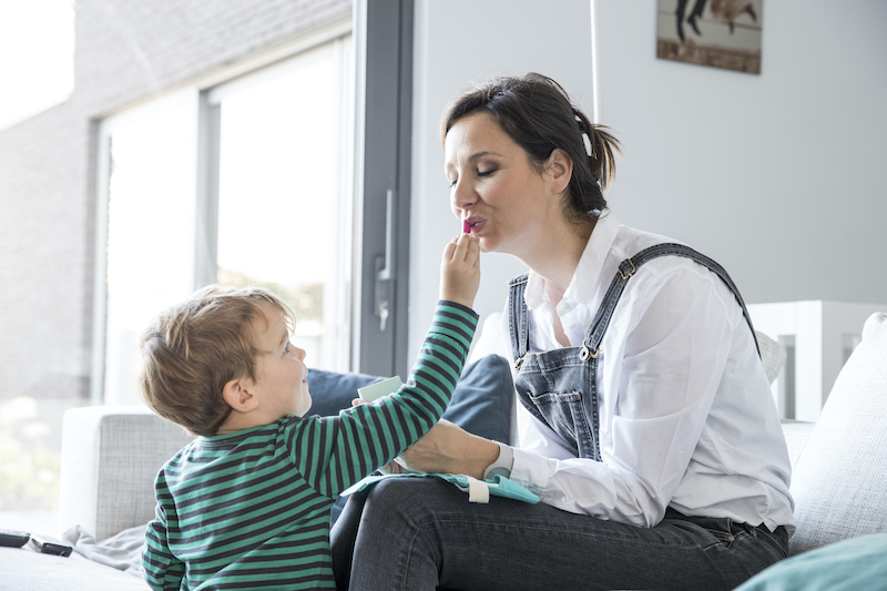 jongen doet lippenstift op lippen van mama