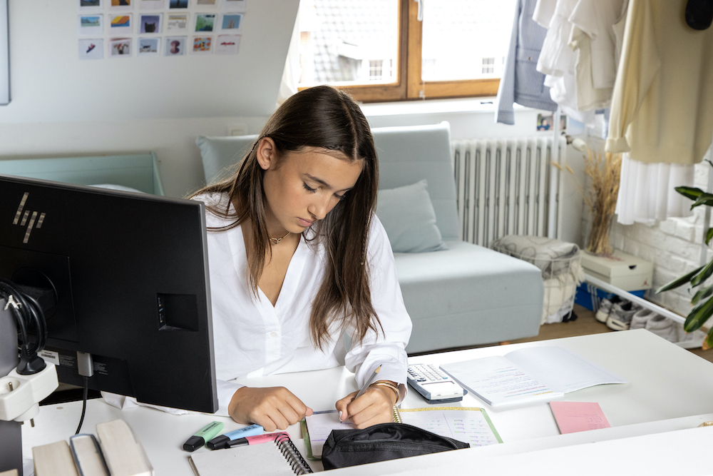Tienermeisje studeert of maakt huiswerk aan bureau