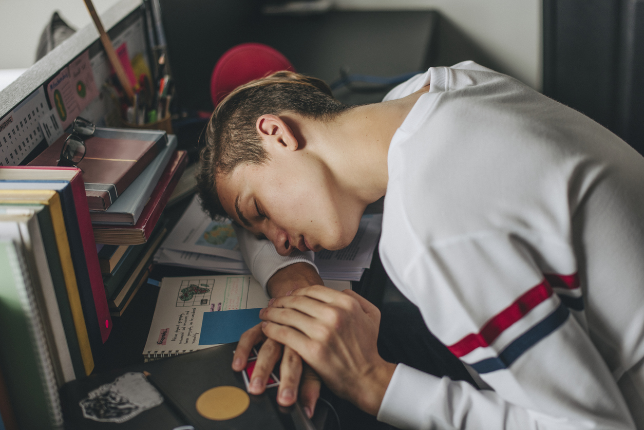 tiener met narcolepsie slaapt op zijn boeken