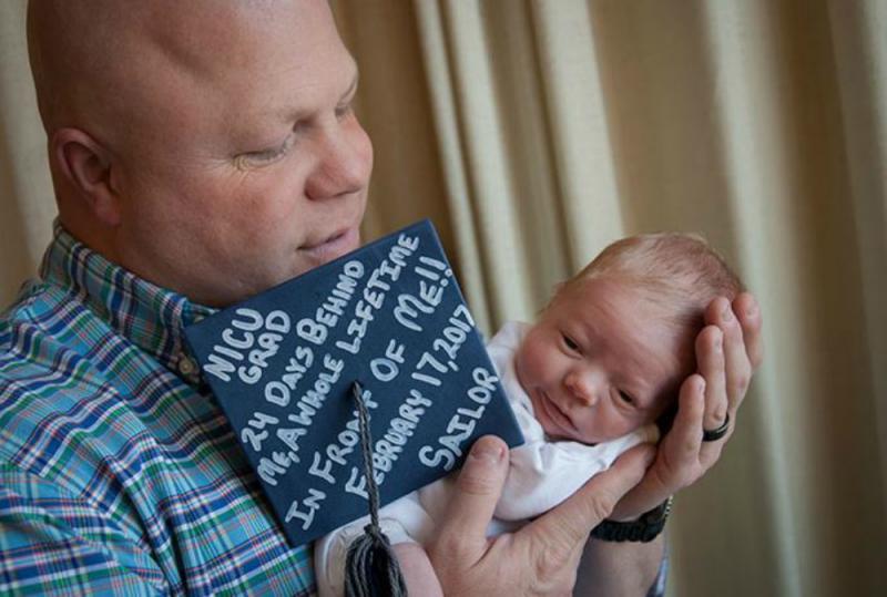 premature baby met afstudeerhoed bij de papa 