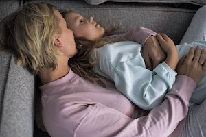 Mama en dochter liggen in pyjama in de zetel