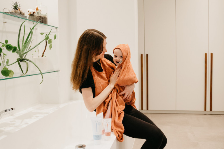 mama met baby in badcape in badkamer