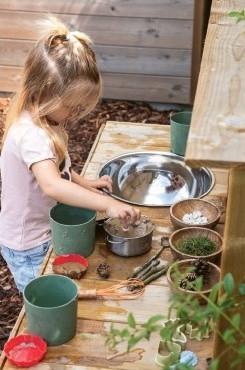 meisje speelt met modder in buitenkeukentje