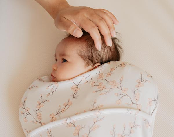 Baby slaapt in inbakerslaapzak in bedje