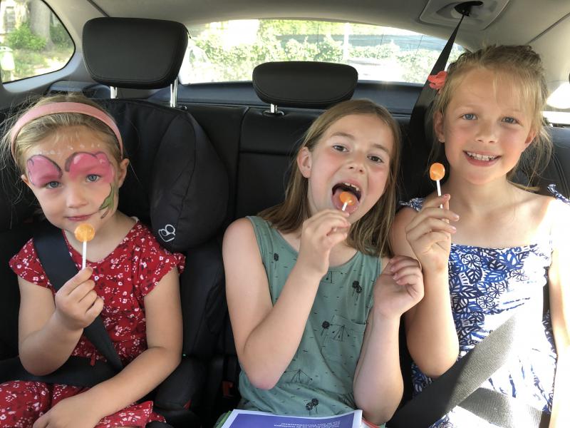 drie meisjes op achterbank auto met lollys
