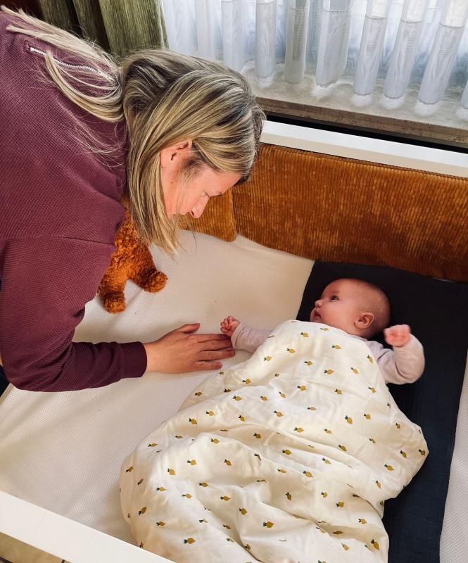 Mama staat aan bedje van baby