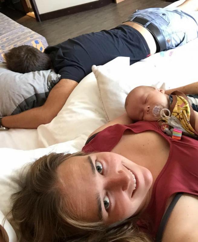 mama met baby en papa die slaapt op bed