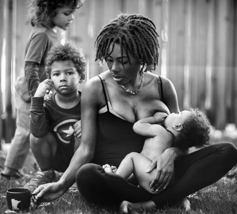 mama geeft borst aan baby, twee kinderen achter haar