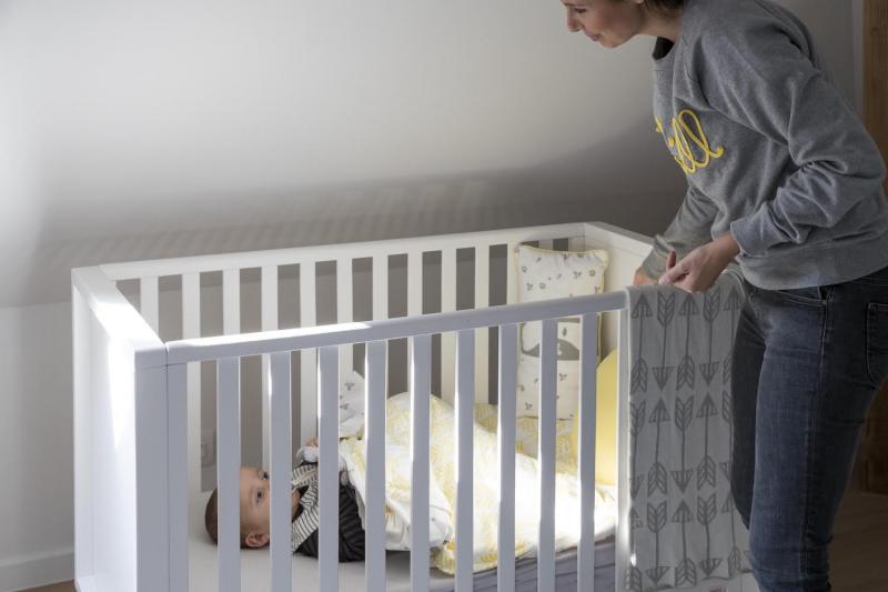 mama staat aan bedje van baby