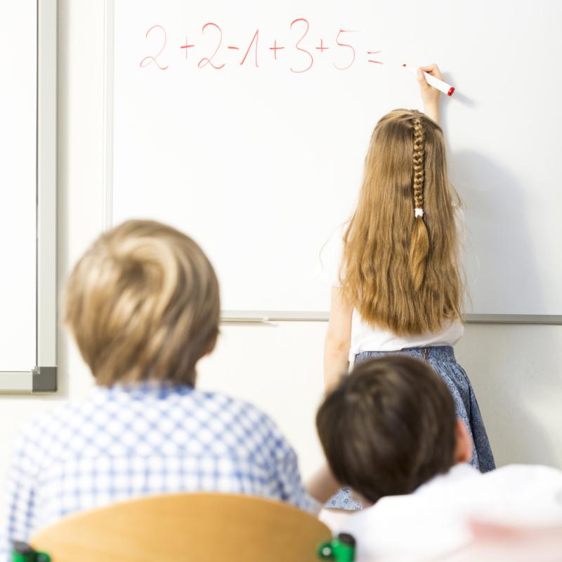 meisje schrijft rekensom op bord